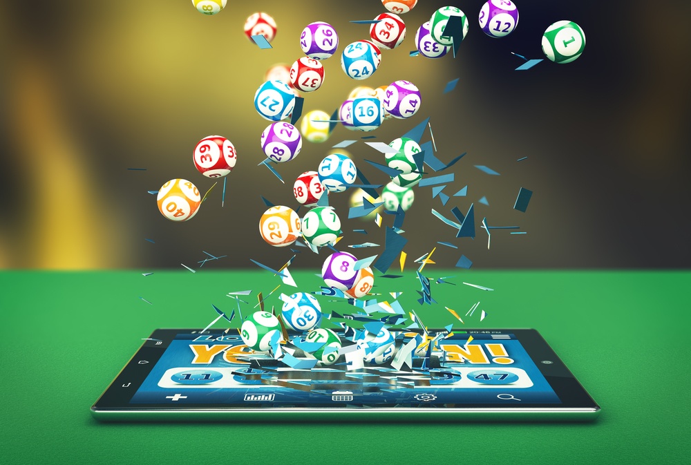 Different Bingo balls exploding out of a tablet lying on top of a green table